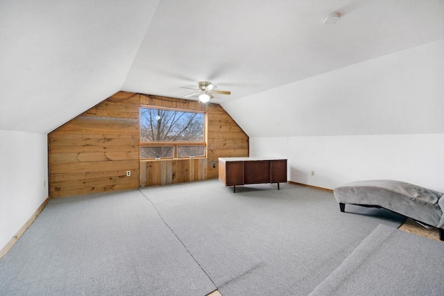 bonus room with wood walls, baseboards, vaulted ceiling, and light colored carpet