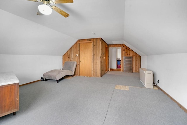 additional living space featuring lofted ceiling, a ceiling fan, light carpet, wood walls, and baseboards