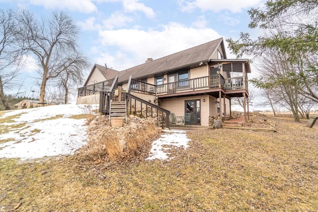 back of property featuring stairway, a chimney, a sunroom, and a deck