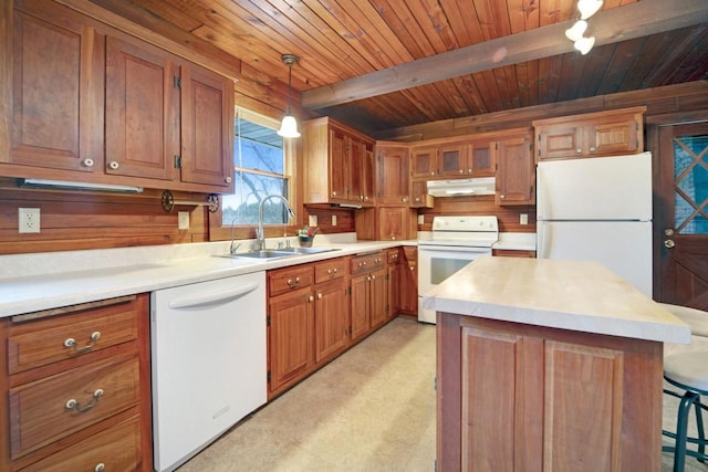 kitchen with under cabinet range hood, white appliances, a sink, brown cabinetry, and beamed ceiling