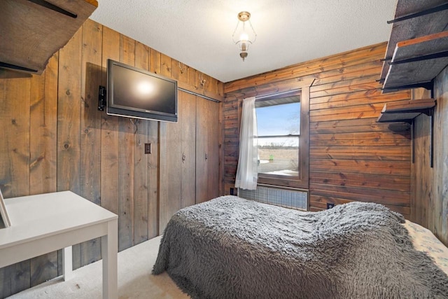 carpeted bedroom with wood walls, a textured ceiling, and a closet