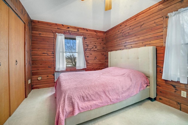 carpeted bedroom with wood walls, a closet, and a ceiling fan