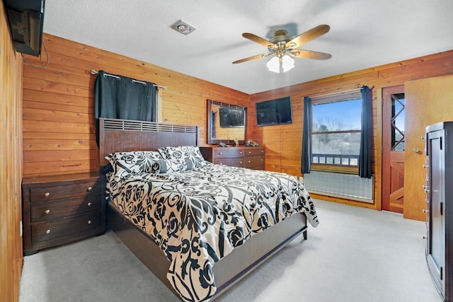 carpeted bedroom featuring wooden walls and a ceiling fan