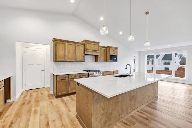 kitchen with brown cabinets, built in microwave, a sink, light wood-type flooring, and stainless steel gas range oven