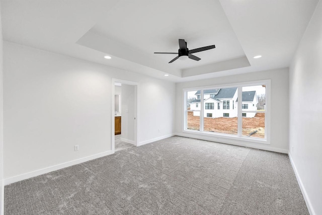 unfurnished room featuring a tray ceiling, recessed lighting, and baseboards