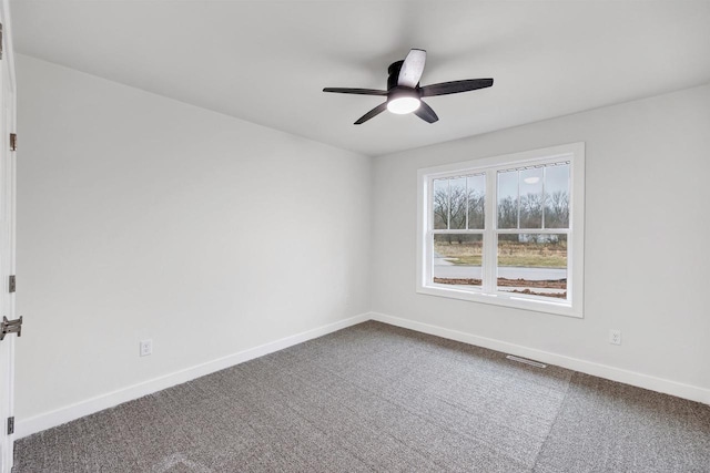 spare room featuring visible vents, dark carpet, baseboards, and ceiling fan