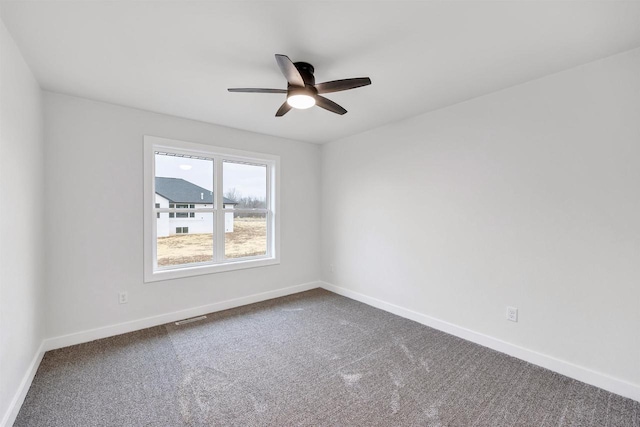 carpeted spare room featuring a ceiling fan, visible vents, and baseboards