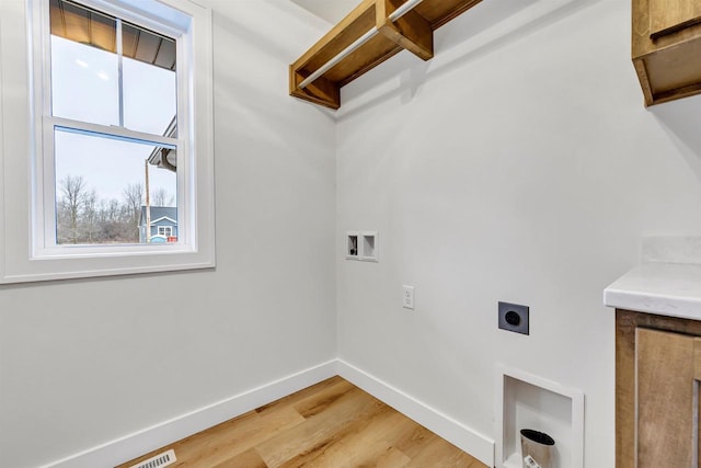 washroom with cabinet space, baseboards, light wood-style floors, washer hookup, and electric dryer hookup