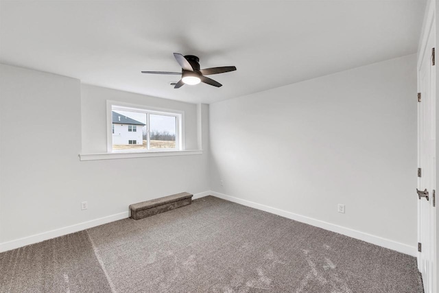 carpeted spare room with ceiling fan and baseboards