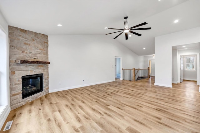 unfurnished living room featuring ceiling fan, a fireplace, visible vents, vaulted ceiling, and light wood-type flooring