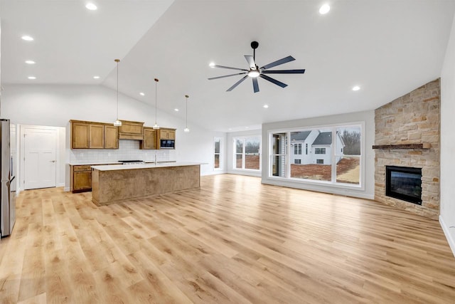 kitchen featuring a kitchen island with sink, a ceiling fan, light wood-style floors, open floor plan, and brown cabinets