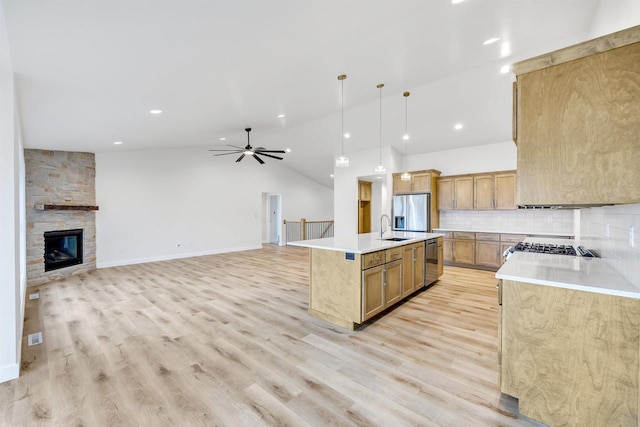 kitchen featuring a sink, light wood-style floors, open floor plan, light countertops, and appliances with stainless steel finishes