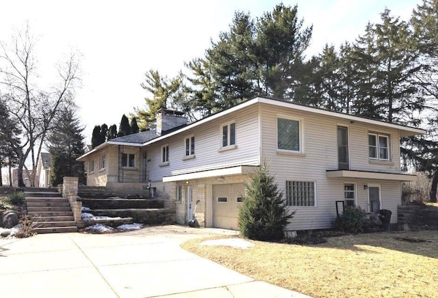 view of front of house featuring driveway, a chimney, an attached garage, and a front yard