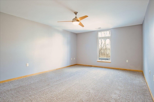 carpeted spare room with visible vents, baseboards, and ceiling fan