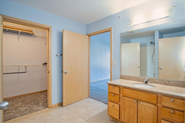 bathroom with tile patterned flooring, a spacious closet, a shower, and vanity