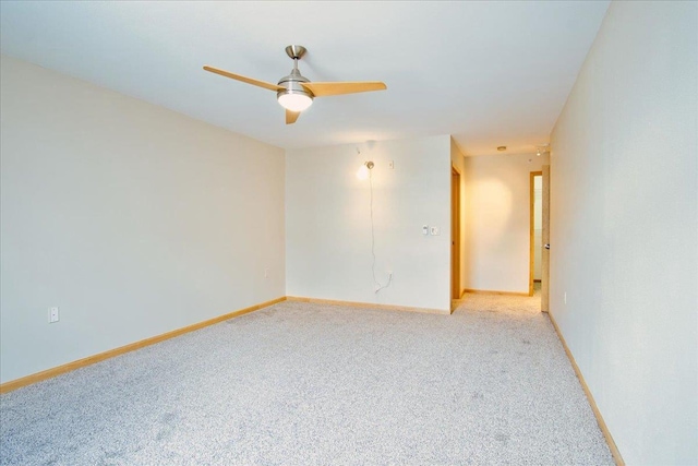 spare room with a ceiling fan, light carpet, and baseboards