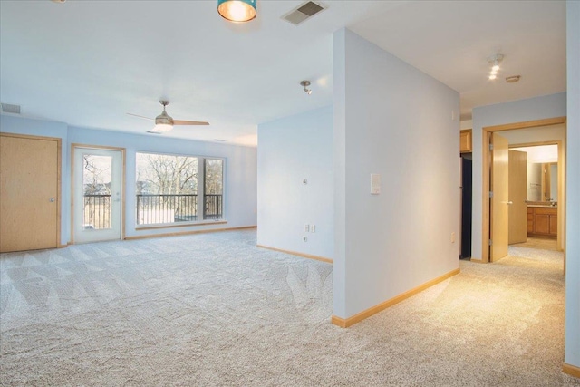 spare room featuring a ceiling fan, light carpet, visible vents, and baseboards