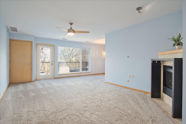 unfurnished living room with visible vents, carpet flooring, ceiling fan, a tile fireplace, and baseboards