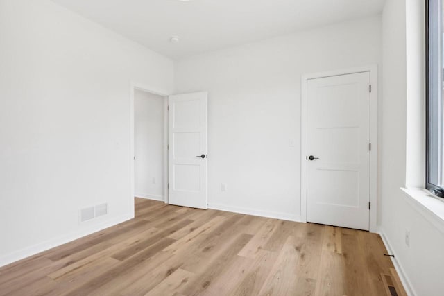 unfurnished bedroom with light wood-style flooring, visible vents, and baseboards