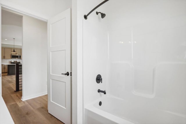 bathroom with bathing tub / shower combination and wood finished floors