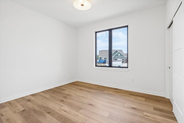 unfurnished bedroom with visible vents, a closet, light wood-style flooring, and baseboards