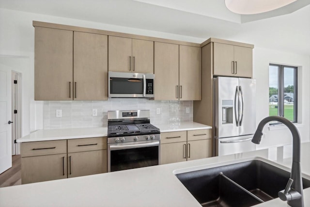 kitchen featuring tasteful backsplash, stainless steel appliances, a sink, and light countertops
