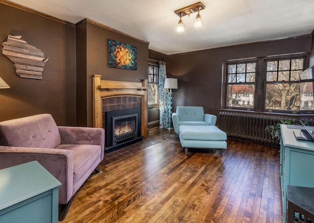 living room featuring radiator, a tiled fireplace, and hardwood / wood-style flooring