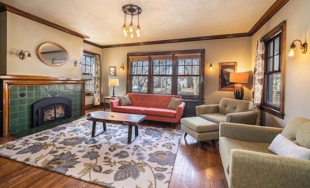 living room featuring a tiled fireplace, crown molding, and wood finished floors