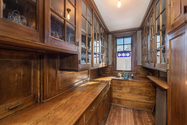 bar with dark wood-type flooring and ornamental molding