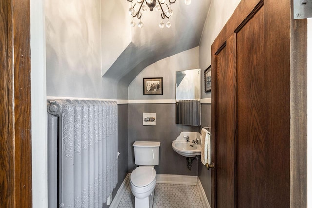 half bath with a sink, baseboards, toilet, and tile patterned flooring