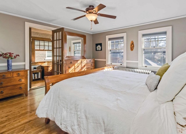 bedroom with wood finished floors, ornamental molding, and a ceiling fan