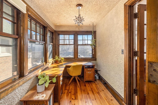 office space featuring light wood finished floors, wallpapered walls, a textured ceiling, and baseboards