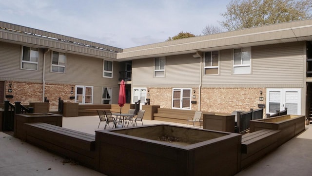 back of house with a patio area, brick siding, and a fire pit