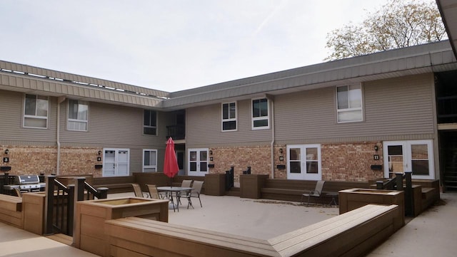 rear view of property featuring entry steps, outdoor dining space, a patio, and brick siding