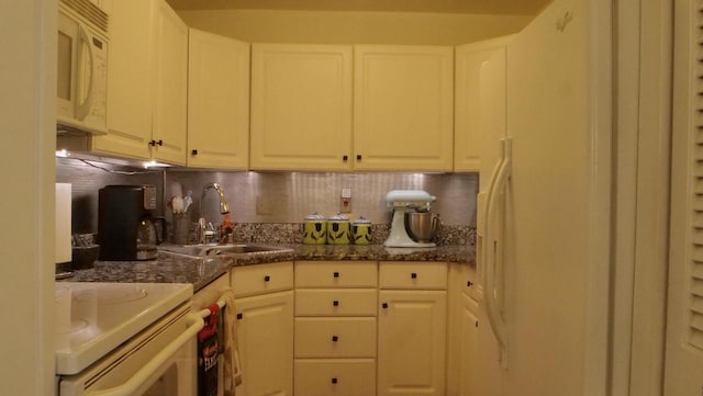 kitchen with white appliances, a sink, backsplash, and dark stone countertops