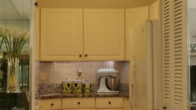 interior details featuring dark stone countertops, white cabinets, and backsplash