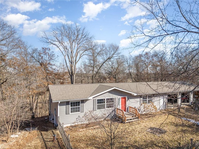 ranch-style house featuring roof with shingles and fence