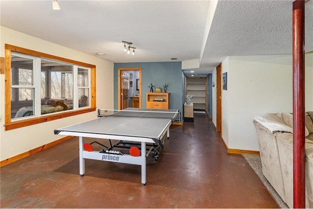 rec room with baseboards, a textured ceiling, and finished concrete flooring