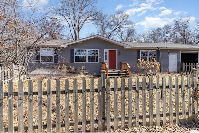 ranch-style home featuring a garage and a fenced front yard