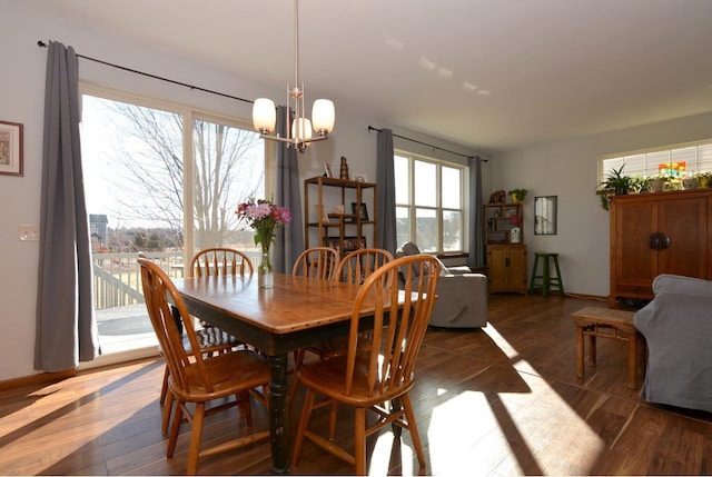 dining space featuring baseboards, a chandelier, and wood finished floors