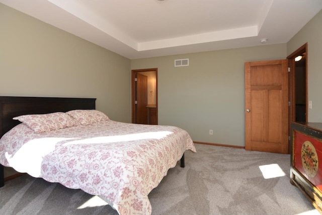 bedroom with a tray ceiling, light colored carpet, visible vents, and baseboards