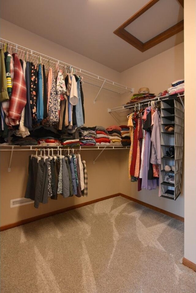 spacious closet featuring attic access and carpet floors