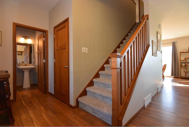 staircase featuring wood-type flooring, visible vents, and baseboards