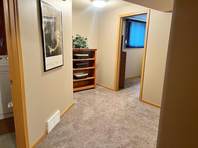 hallway featuring carpet floors, baseboards, visible vents, and washer / clothes dryer