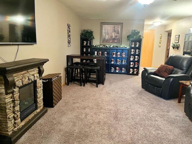 carpeted living room featuring a stone fireplace