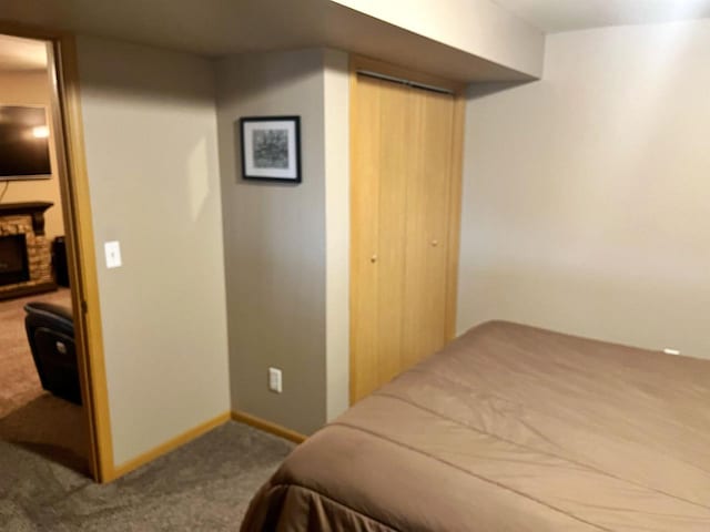 bedroom with carpet, a closet, a fireplace, and baseboards