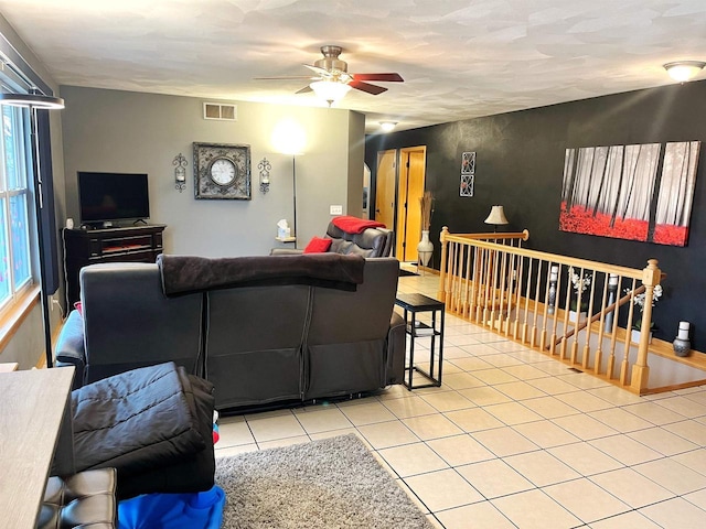 tiled living room featuring a ceiling fan and visible vents