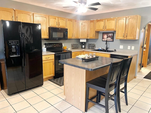 kitchen featuring light tile patterned floors, light brown cabinetry, a ceiling fan, a sink, and black appliances