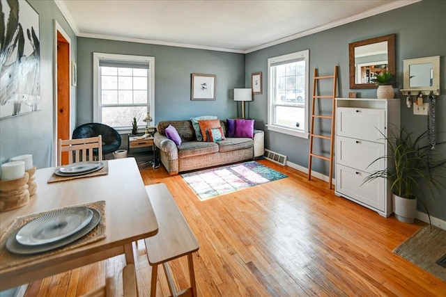 living room with visible vents, baseboards, wood finished floors, and ornamental molding