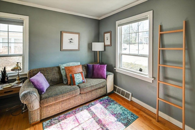 living area featuring visible vents, crown molding, baseboards, and wood finished floors